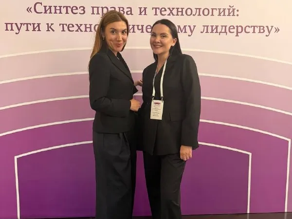 ЕАПК 2026: Ксения (справа, бейдж) с коллегой у пресс-волла XIX сессии «Синтез права и технологий»